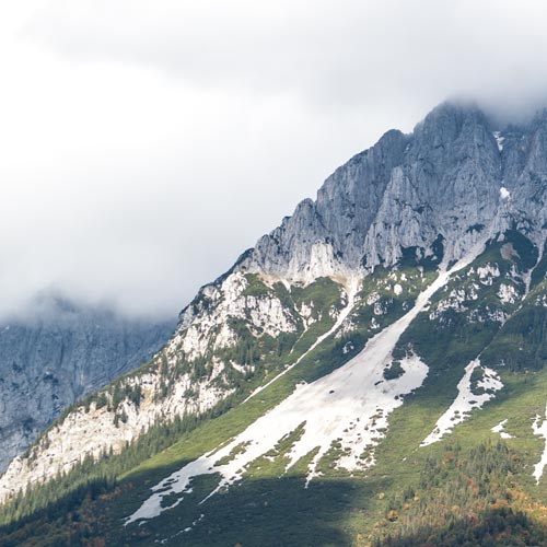 Blick auf eine Bergkuppe, die von Nebelwolken umhüllt ist